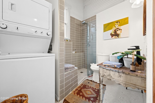 full bathroom featuring a shower stall, stacked washer / dryer, toilet, and tile patterned floors