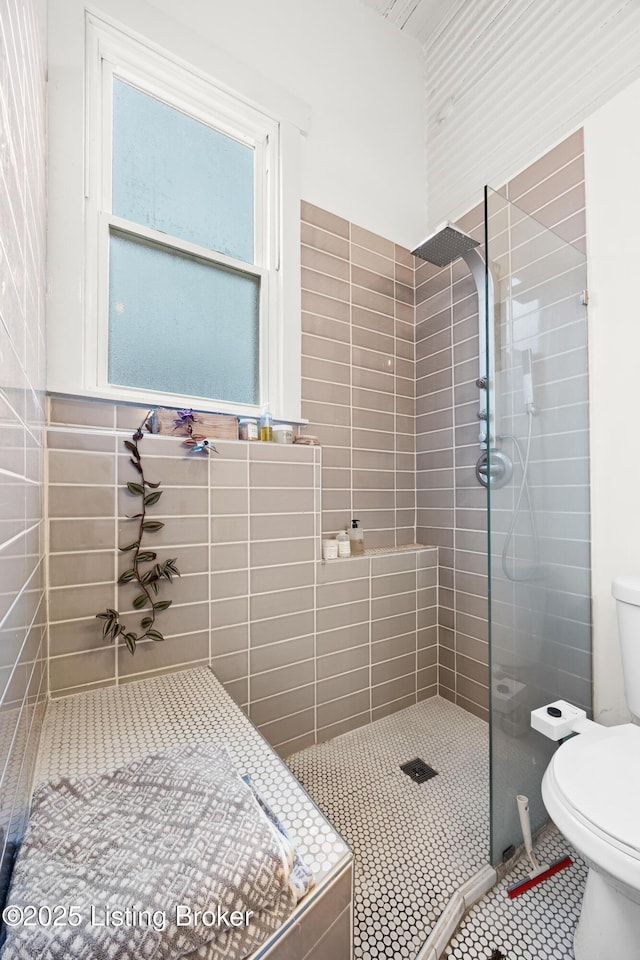 full bath with tile patterned floors, toilet, and tiled shower