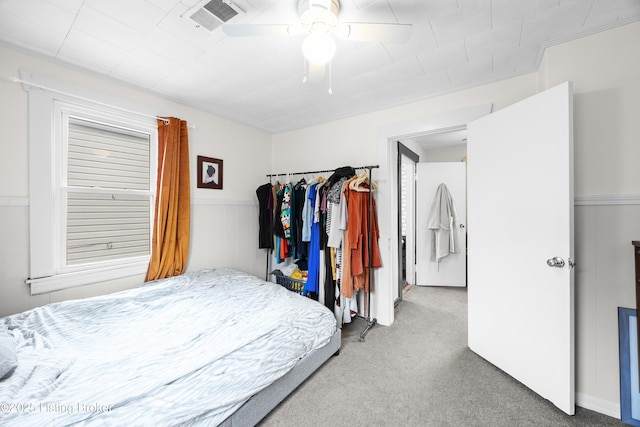 bedroom featuring a wainscoted wall, a ceiling fan, visible vents, and carpet floors