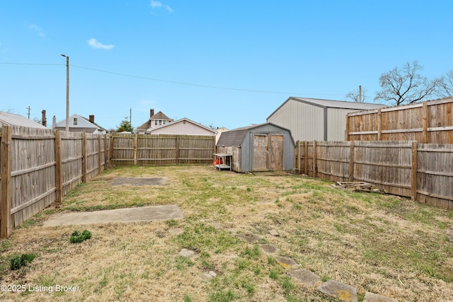 view of yard with an outdoor structure, a fenced backyard, and a shed