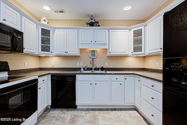 kitchen with dark countertops, visible vents, black appliances, white cabinetry, and a sink