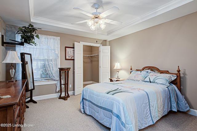 carpeted bedroom featuring a tray ceiling, baseboards, and ornamental molding