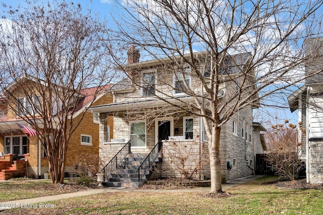 view of front of house featuring brick siding, a front yard, and a chimney