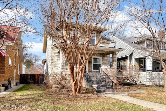 view of front facade featuring a porch, central AC unit, stone siding, and a front lawn