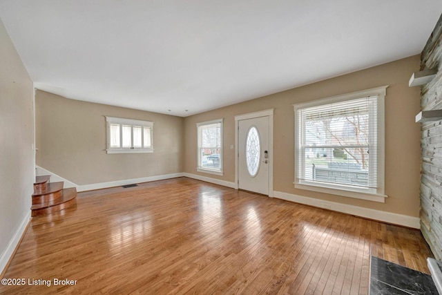 foyer entrance featuring visible vents, baseboards, hardwood / wood-style floors, and stairs