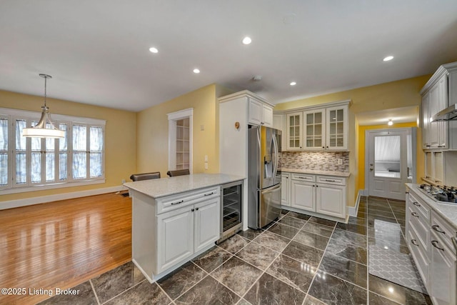 kitchen with backsplash, glass insert cabinets, wine cooler, appliances with stainless steel finishes, and a peninsula