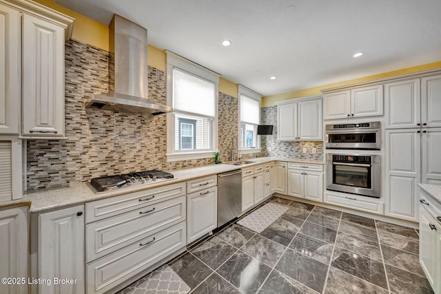 kitchen with recessed lighting, a sink, stainless steel appliances, wall chimney exhaust hood, and backsplash