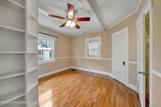 empty room featuring baseboards, beam ceiling, and wood finished floors