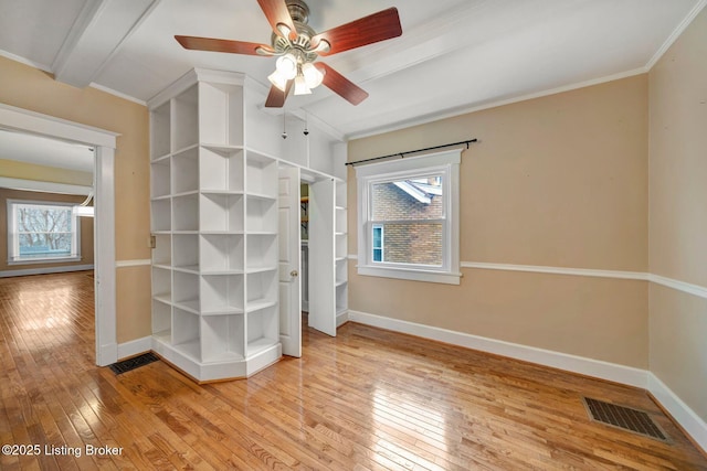 unfurnished bedroom featuring visible vents, beamed ceiling, ornamental molding, light wood finished floors, and baseboards