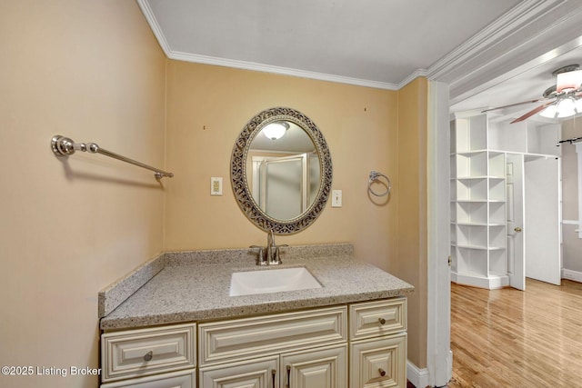 bathroom with ceiling fan, wood finished floors, vanity, and ornamental molding