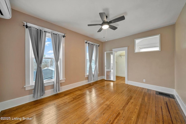 unfurnished room with visible vents, baseboards, light wood-style floors, and a wall mounted AC