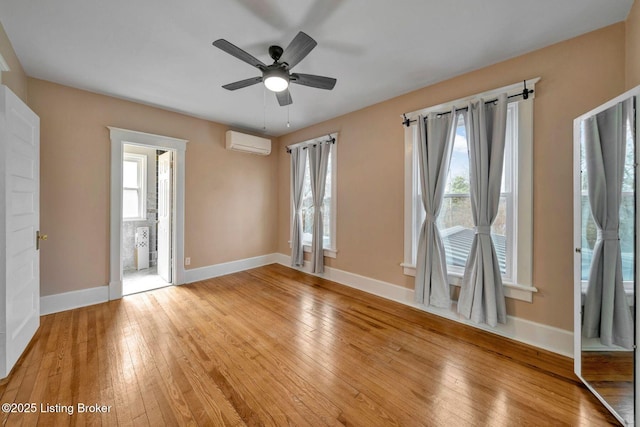 unfurnished room featuring a wall mounted air conditioner, a healthy amount of sunlight, and light wood finished floors