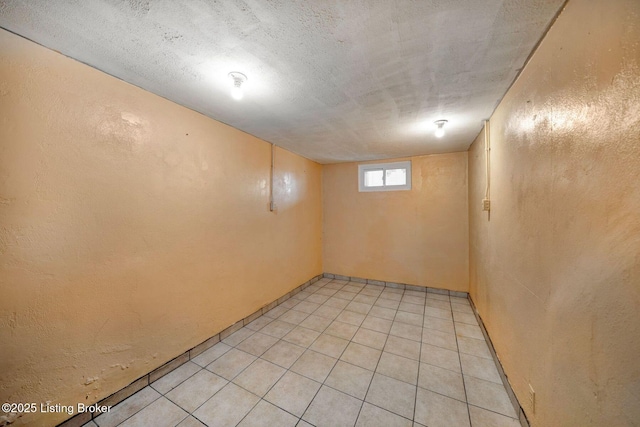 below grade area featuring light tile patterned flooring and a textured wall