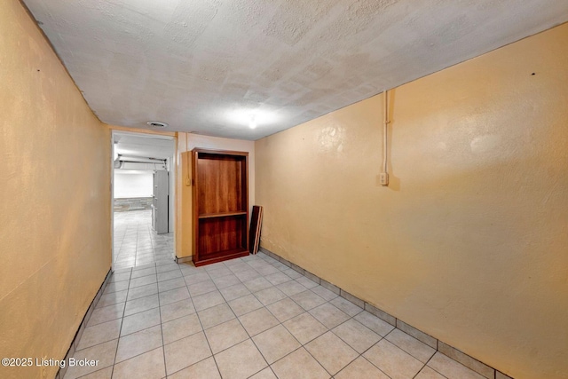 empty room featuring light tile patterned floors, visible vents, a textured ceiling, and a textured wall