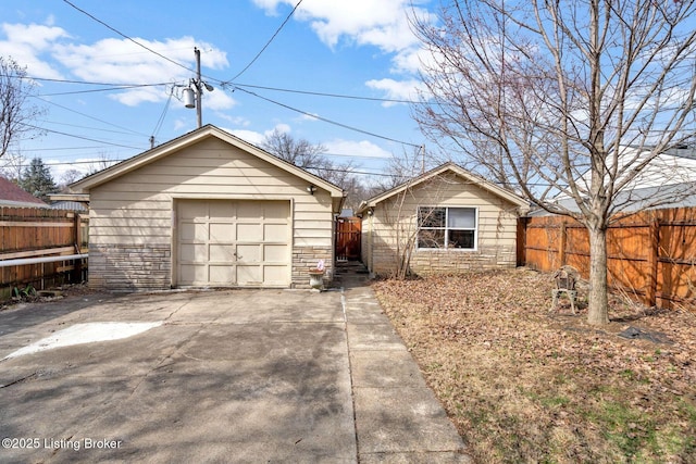 view of front facade featuring a detached garage, fence, concrete driveway, an outdoor structure, and stone siding