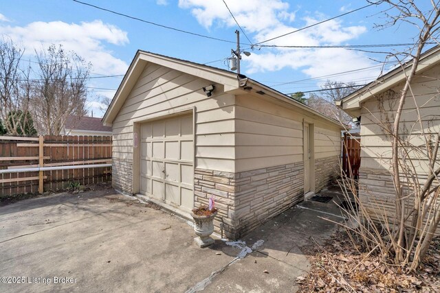 detached garage featuring driveway and fence