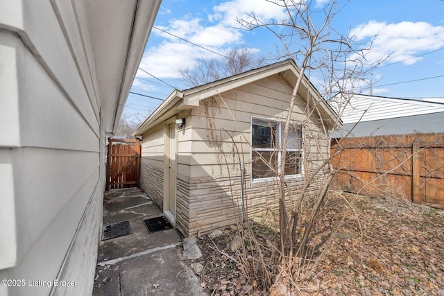 view of property exterior with fence and stone siding