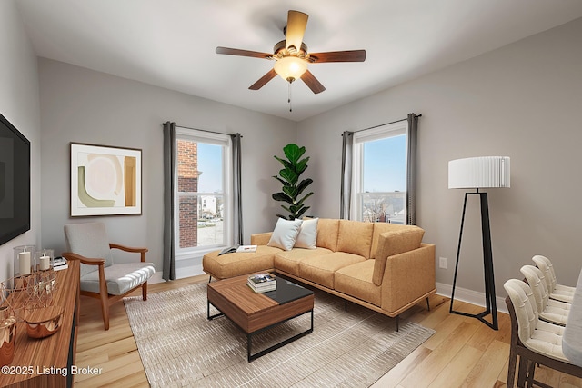 living area with ceiling fan, baseboards, and light wood-style floors