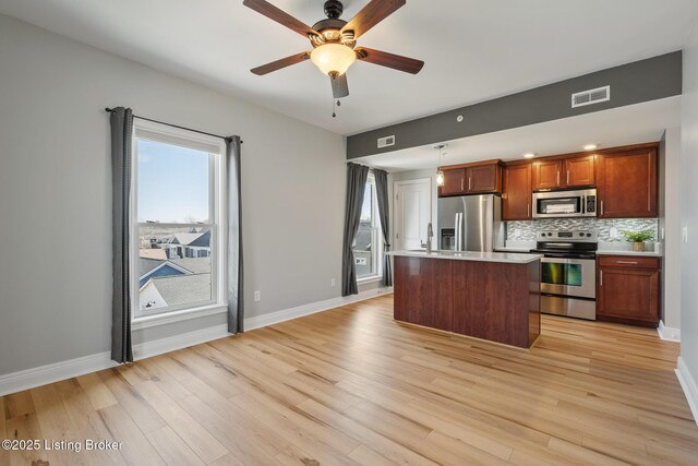 kitchen featuring visible vents, a sink, tasteful backsplash, a center island, and appliances with stainless steel finishes