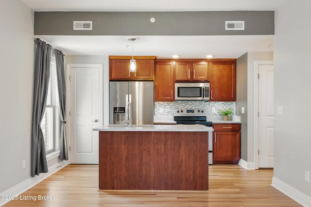 kitchen featuring light wood-type flooring, stainless steel appliances, visible vents, and decorative backsplash