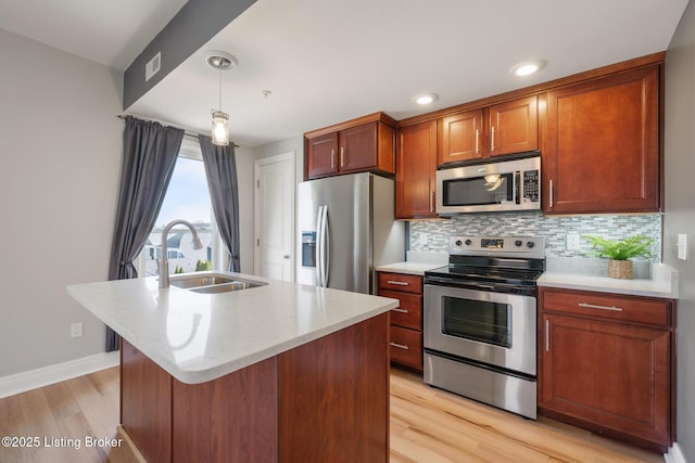 kitchen featuring light wood-style flooring, a sink, decorative backsplash, light countertops, and appliances with stainless steel finishes