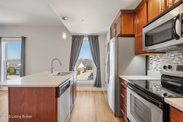 kitchen featuring a wealth of natural light, appliances with stainless steel finishes, brown cabinetry, and a sink