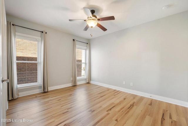 spare room featuring light wood-type flooring, baseboards, and ceiling fan