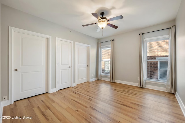 unfurnished bedroom featuring baseboards, light wood-style floors, and a ceiling fan