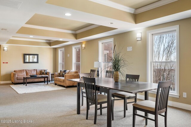 dining space with a tray ceiling, crown molding, light colored carpet, and baseboards