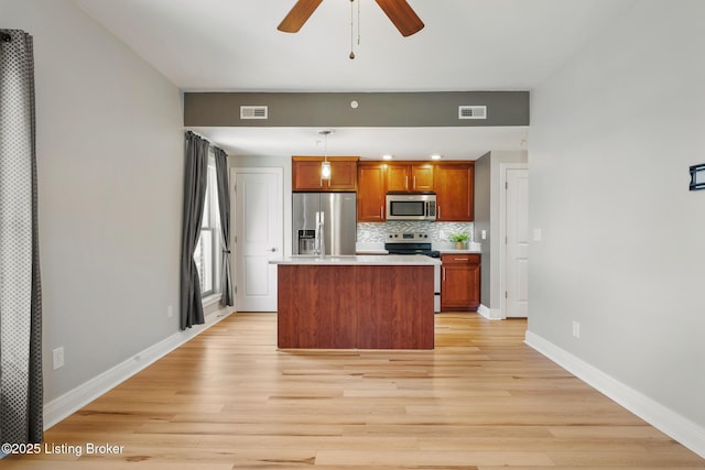 kitchen featuring a kitchen island, tasteful backsplash, stainless steel appliances, light countertops, and baseboards