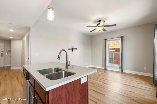 kitchen with a sink, light wood-type flooring, and baseboards