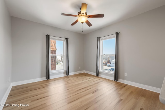 empty room featuring ceiling fan, light wood-type flooring, and baseboards