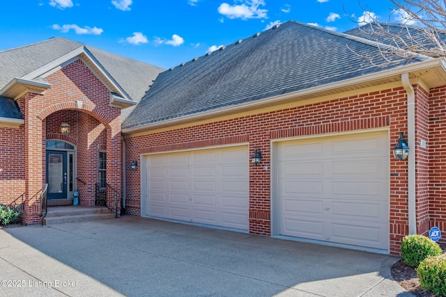 view of front of house featuring brick siding, an attached garage, concrete driveway, and roof with shingles