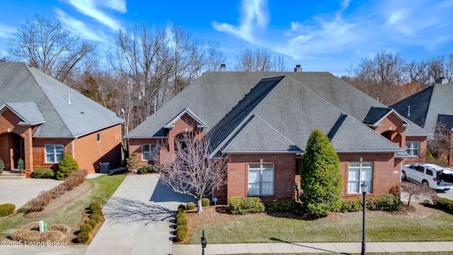 traditional home featuring concrete driveway, brick siding, and a chimney