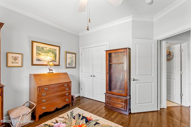 sitting room featuring baseboards, crown molding, a ceiling fan, and wood finished floors