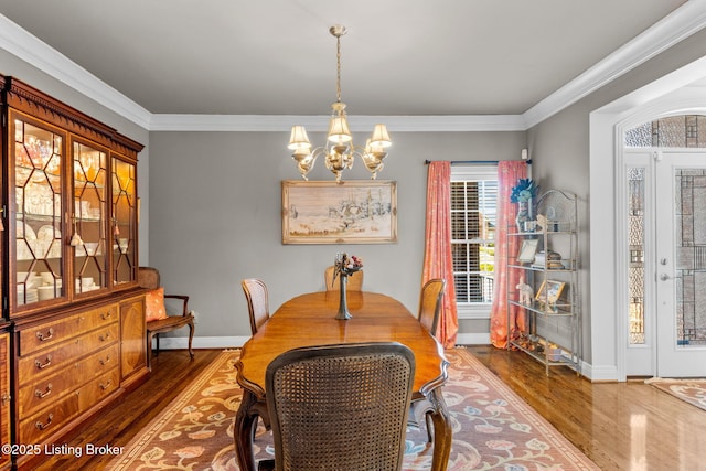 dining area featuring a chandelier, ornamental molding, and wood finished floors