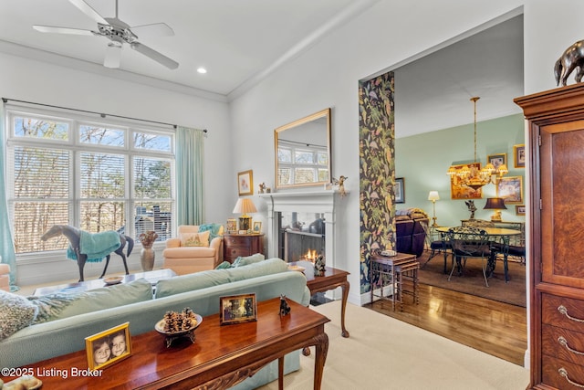 living area featuring plenty of natural light, a warm lit fireplace, wood finished floors, and a ceiling fan