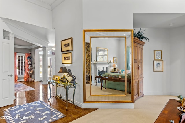 interior space featuring wood finished floors, baseboards, ornamental molding, and ornate columns