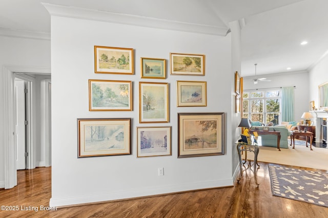 hall featuring recessed lighting, wood finished floors, baseboards, and ornamental molding