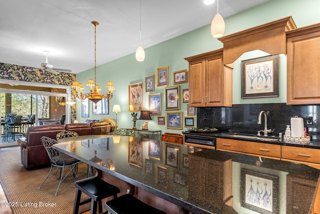 kitchen featuring a breakfast bar area, a sink, hanging light fixtures, open floor plan, and backsplash