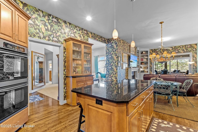 kitchen featuring double wall oven, open floor plan, wallpapered walls, and light wood-style floors