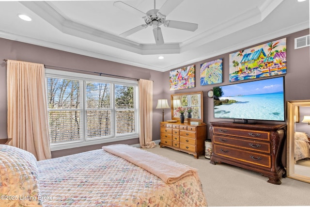 carpeted bedroom with visible vents, a raised ceiling, ornamental molding, and a ceiling fan