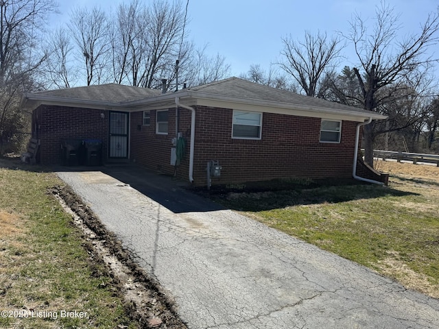 view of front of home featuring driveway, a front yard, and brick siding