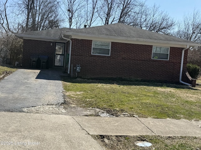 view of front of house with aphalt driveway, a front lawn, and brick siding