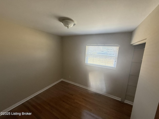 empty room with dark wood-type flooring and baseboards