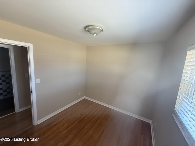 spare room with dark wood-style floors and baseboards