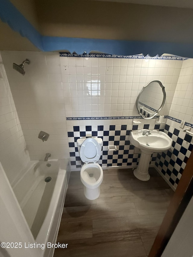 bathroom with  shower combination, tile walls, toilet, and wood finished floors