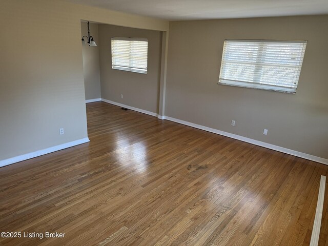 unfurnished room with a healthy amount of sunlight, visible vents, baseboards, and wood finished floors