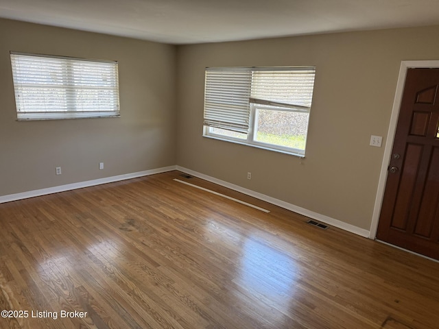 spare room featuring baseboards, visible vents, and wood finished floors