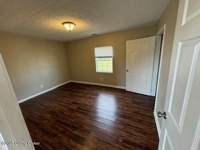 unfurnished bedroom featuring a textured ceiling, dark wood-type flooring, and baseboards